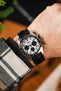 Black Artem sailcloth watch strap with black stitching fitted to a Seiko Prospex with panda dial and silver pusher and crown, on wrist with check flannel shirt.