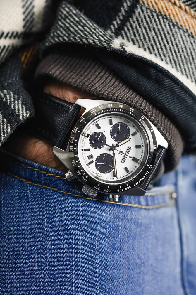 Black Artem Classic Sailcloth Strap fitted to panda and silver seiko prospex speedtimer with chronograph on wrist with flannel shirt and blue denim jeans 