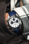 Navy Blue Artem Straps Classic Sailcloth watch strap fitted to Seiko Panda chronograph speedtimer on wrist with hand in pocket of grey trousers and white and black flannel shirt. 