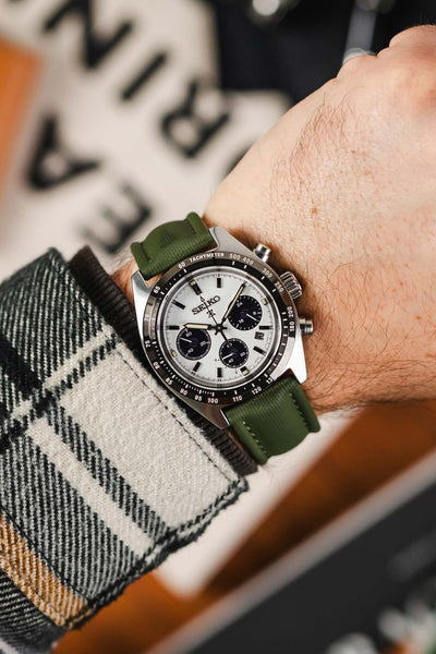 Green Artem sailcloth classic watch strap fitted to Panda Seiko Prospex Speedtimer watch  worn on wrist with check flannel shirt. 