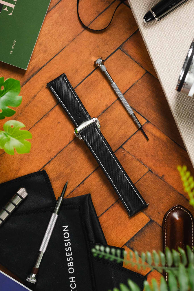 Artem Straps Loop-less Butterfly clasp in polished and brushed stainless steel fitted to Artem Straps Loop-Less Sailcloth watch strap in Black and white stitching on wooden table 