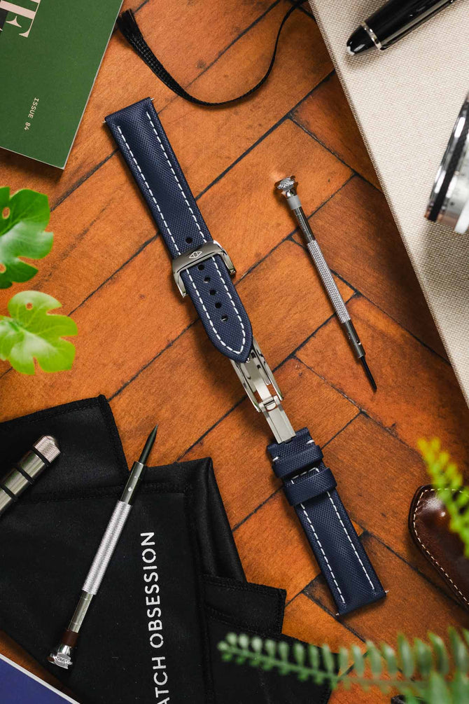 Artem Straps RM style deployment clasp in brushed and polished solid stainless steel opened and fitted to Artem Straps Classic Sailcloth watch strap in Navy blue with white stitching without a fitted timepiece on wooden table