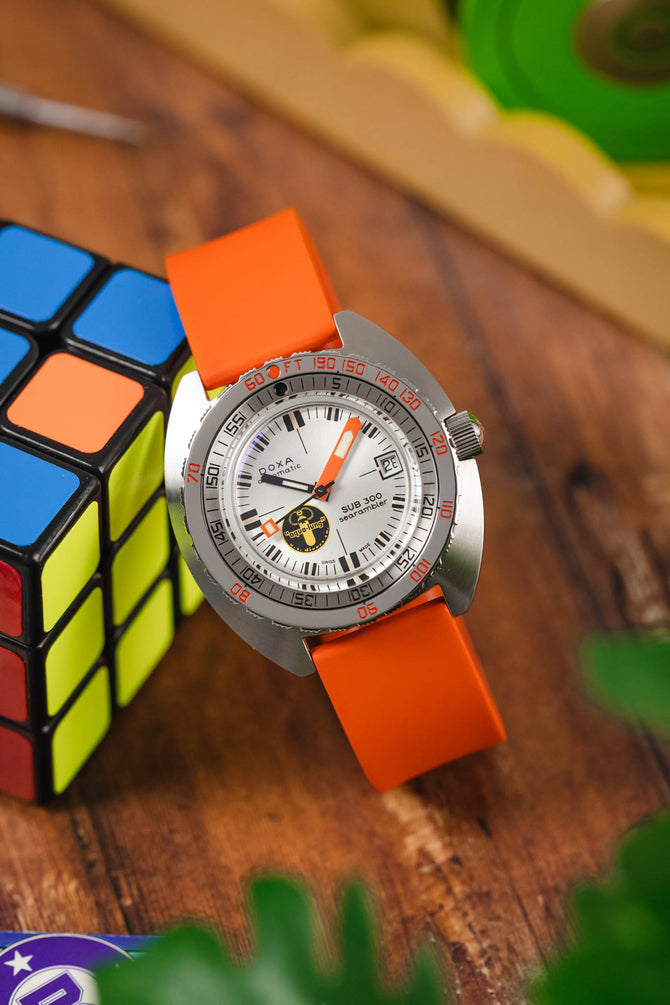 Doxa Sub 300 Searambler Silver Lung Limited Edition fitted to Orange Bonetto Centurini 270 Rubber watch strap tilting on rubiks cube 