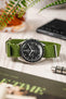 Omega Speedy Watch lay on wooden table with green recycled polyester military strap with silver buckle