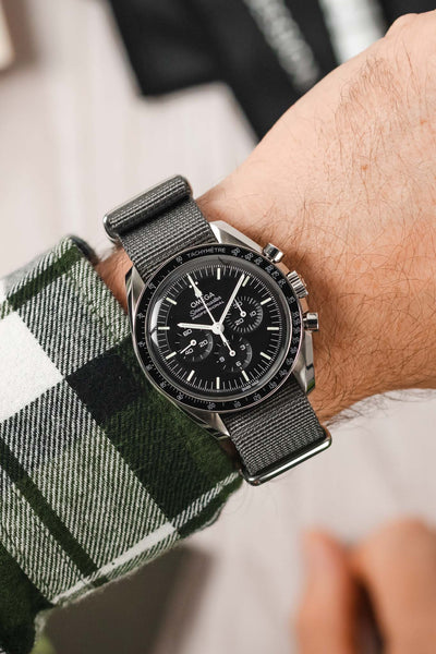 Wrist wearing a checked shirt and an Omega Watch on Grey Military Style Strap