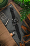 Open watch roll with Omega Speedmaster fitted with RIOS 1931 Black Waging strap with tools and knives in a moody scene
