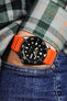 Seiko 5 Sports SRPD55K3 with orange Bonetto Centurini 284 Premium Rubber Strap on wrist with hand in pocket of denim trousers