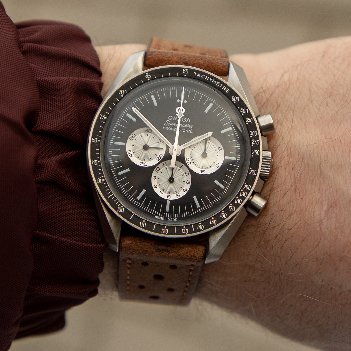 JPM Racing strap in peanut on the wrist with Omega Speedmaster