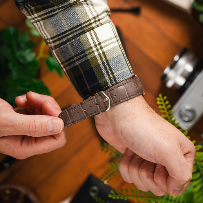 man wearing a hirsch duke embossed alligator leather watch strap with a gold buckle.