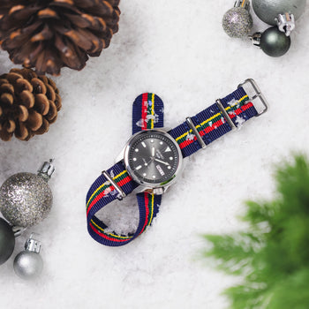 A Seiko 5 Sport fitted to a Christmas Nylon Strap lay in the snow surrounded by Christmas baubles, pine cones and a Christmas tree