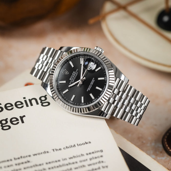 A detailed shot of a Rolex Datejust 41 (126334-0018) placed on an open book titled 