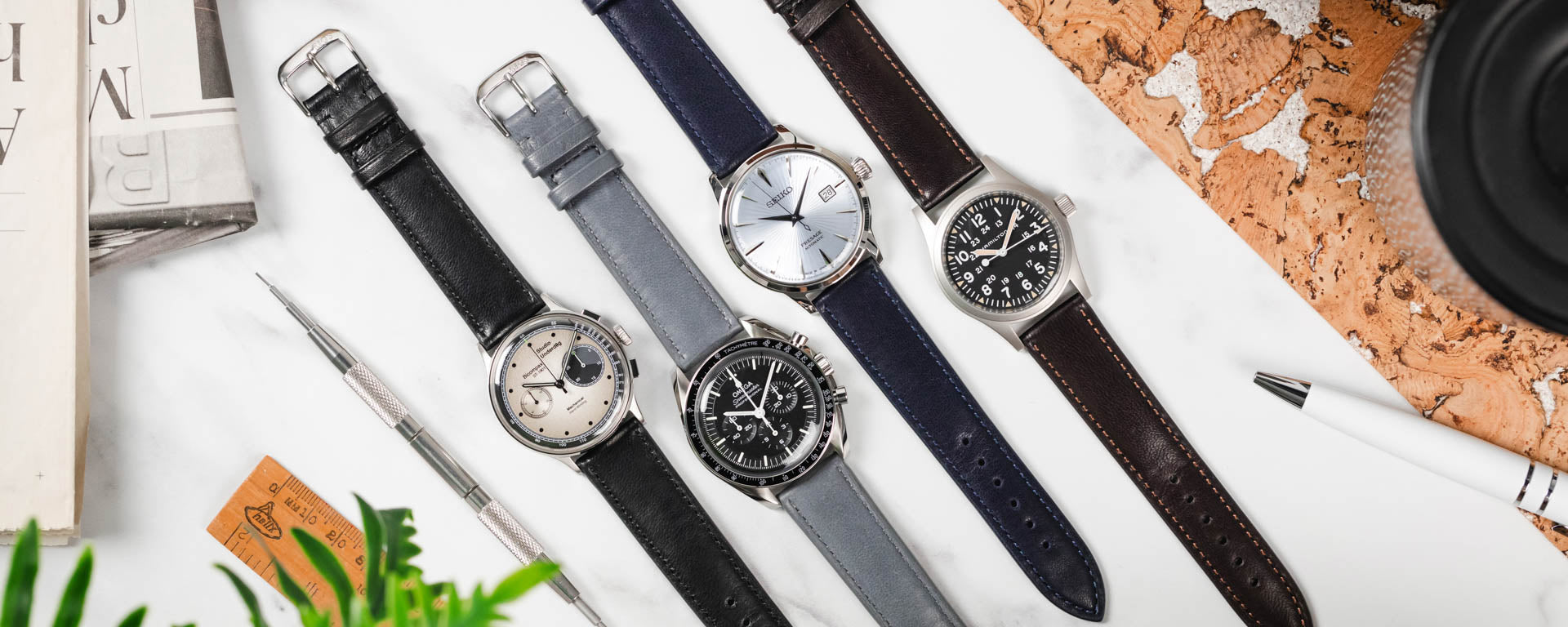 Lay Flat image of four watches, Omega Speedmaster Professional, Studio Underd0g Go0fy Panda, Seiko Presage Cocktail Time & Hamilton Khaki Field, fitted to various colours of RIOS1931 Merino Genuine Lambskin Strap against a marble background