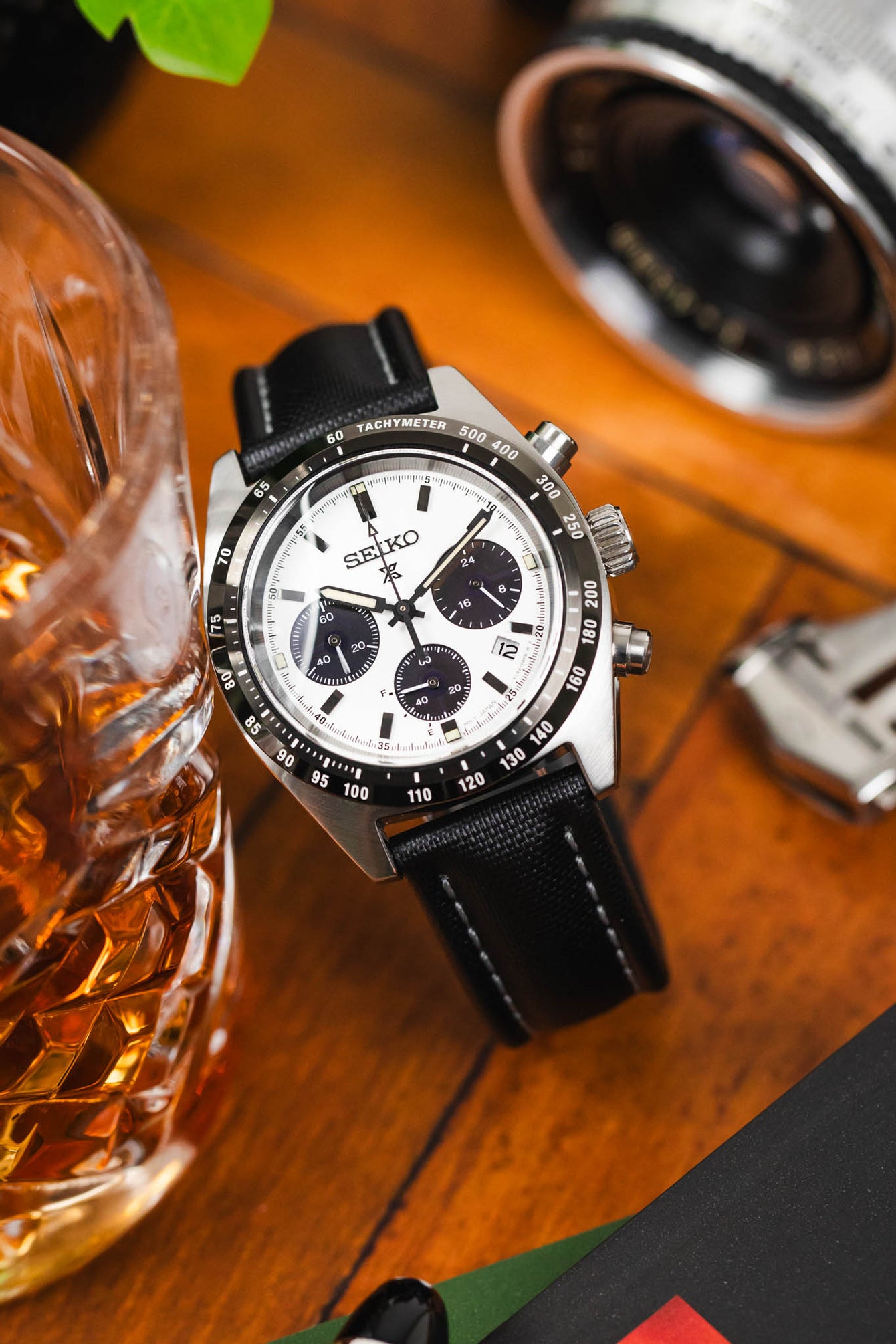 Curved black Artem Classic Sailcoth with grey stitching watch strap fitted to panda Seiko prospex speedtimer with chronograph and brown table. 