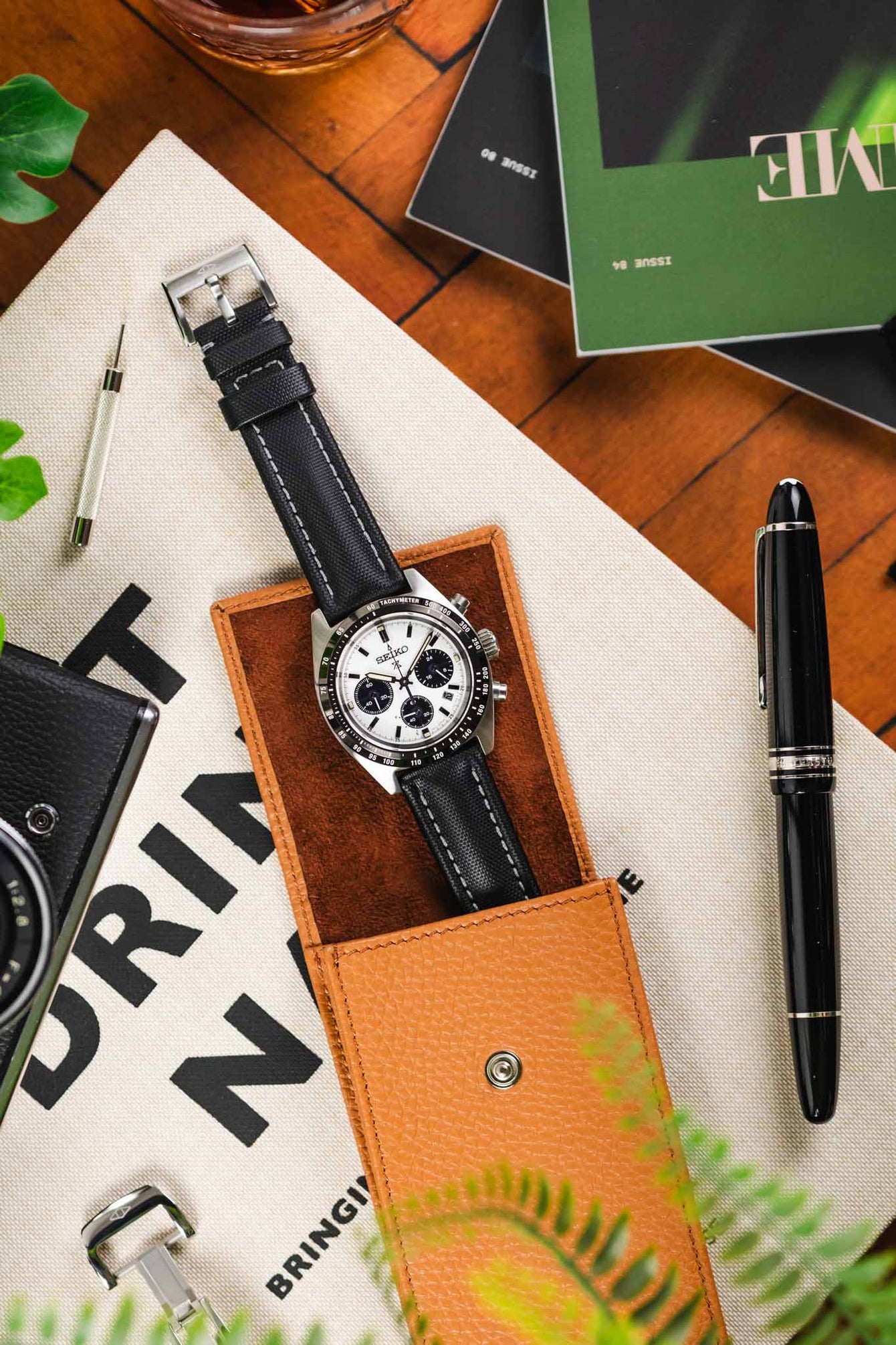 High angle shot of face up panda Seiko Prospex speedetime and black chronograph with black Artem Straps classic sailcloth with grey stitching and stainless steel buckle in beige leather watch case.
