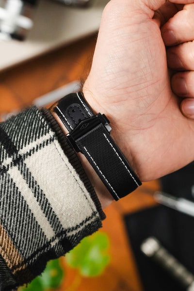 Artem Loop-less deployment clasp in DLC black on black Artem Loop-Less sailcloth watch strap with white stitching on wrist with flannel shirt