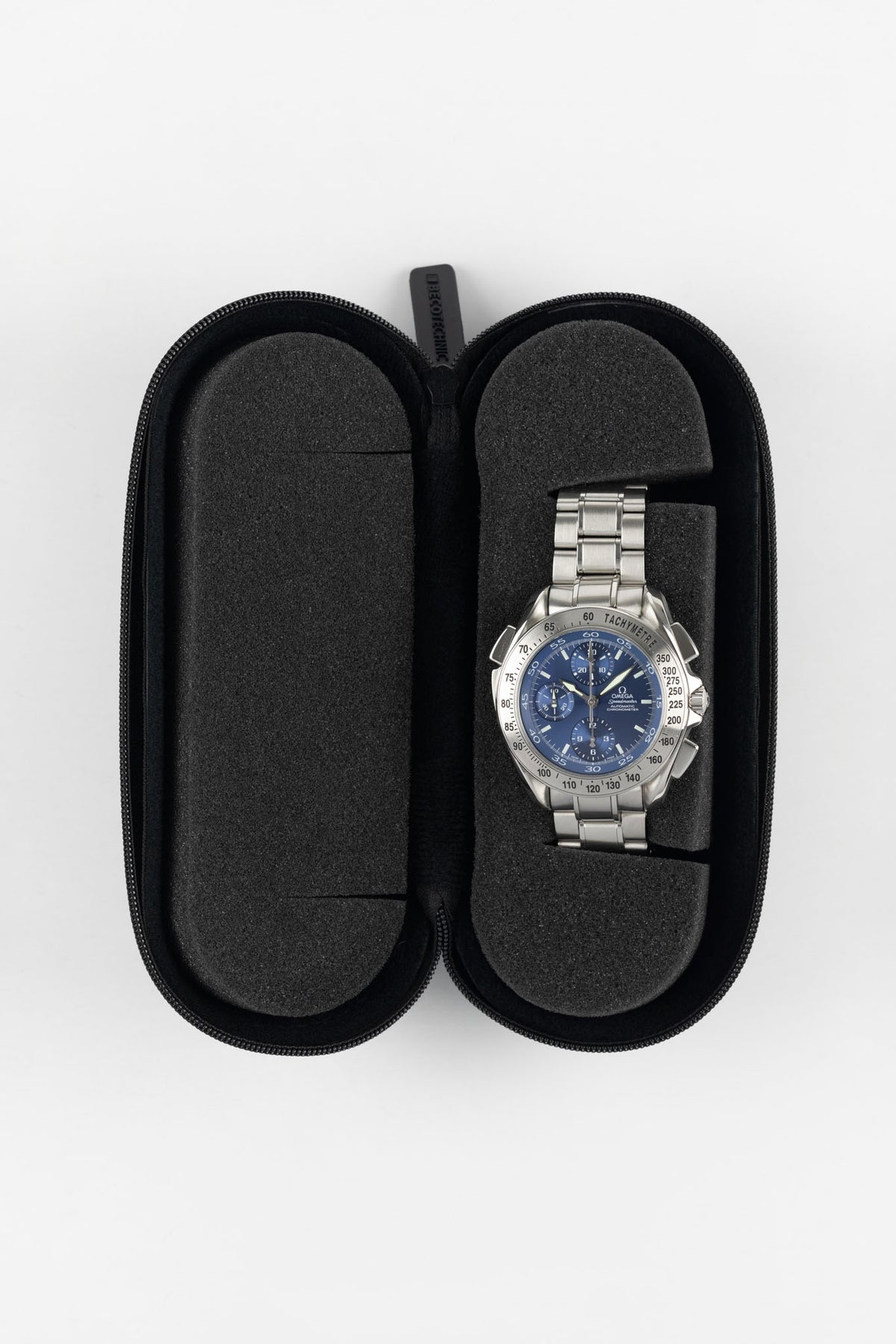 Open black hard-shell watch travel case with foam cushioning, showcasing a stainless steel chronograph watch secured within a protective padded insert.