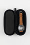 Open black hard-shell watch travel case with a foam-lined interior, displaying a wristwatch with a brown leather strap securely held in place for protection and storage.