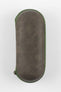 Closed oval-shaped watch travel case with a textured brown exterior and green zipper trim, shown upright against a plain light background.