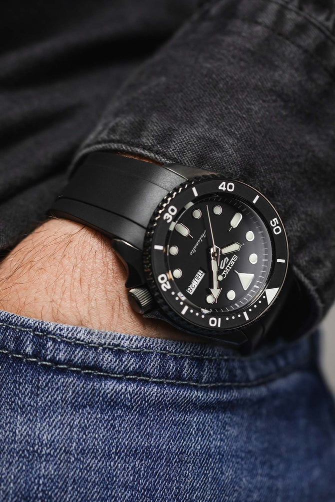 Black Seiko SKX style watch with black FKM rubber Crafter Blue dive strap, hand in pocket