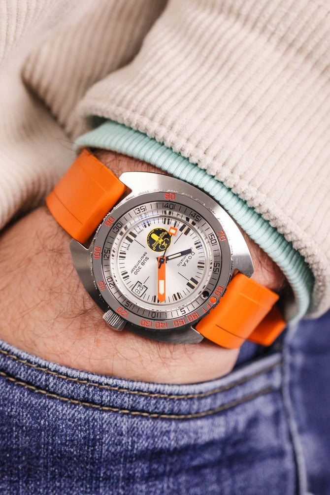 Pocket shot of a Doxa Sub 300 in jeans pocket with turquoise hoodie and cream cord shirt, the watch is fitted to a orange rubber strap
