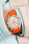 Pocket shot of a Omega X Swatch Mission to Jupiter MoonSwatch in the pocket of a turquoise hoodie and cream cord shirt, the watch is fitted to a Orange rubber strap