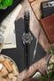 Unimatic dive watch on a black alligator-grain leather strap with cream contrast stitching, displayed with vintage accessories and watchmaking tools on a rustic wooden surface.
