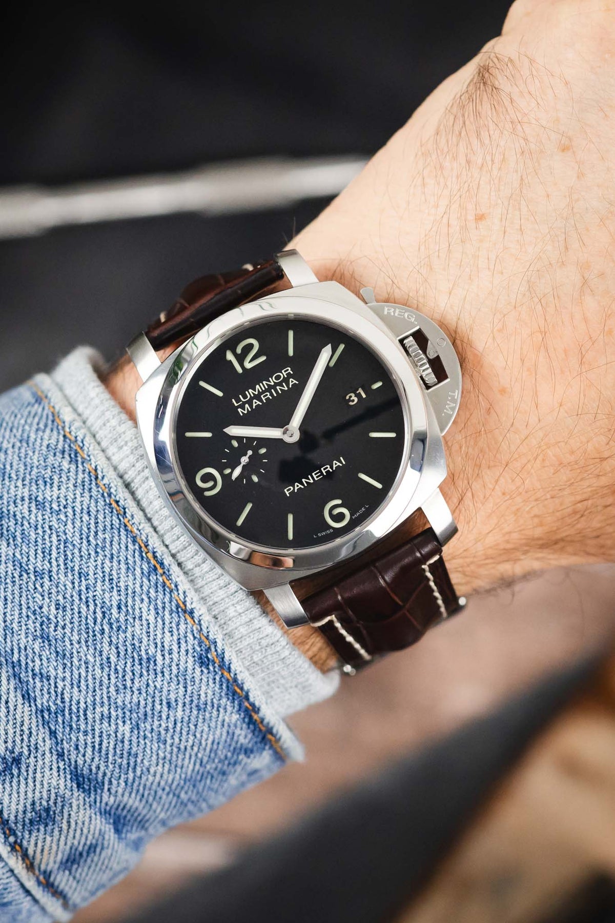 Panerai Luminor Marina on a dark brown alligator-grain leather strap with cream contrast stitching, shown on wrist with a black dial and signature crown guard.