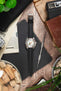 Doxa dive watch on a black carbon-fibre-pattern leather strap with white contrast stitching, displayed with vintage accessories on a rustic wooden surface.