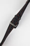Close-up of a black padded leather rally-style watch strap with contrasting red stitching, dual keeper loops, multiple adjustment holes, and a polished stainless steel buckle, displayed diagonally on a light grey background to highlight the supple leather texture, tapered profile, cushioned construction, and motorsport-inspired design.