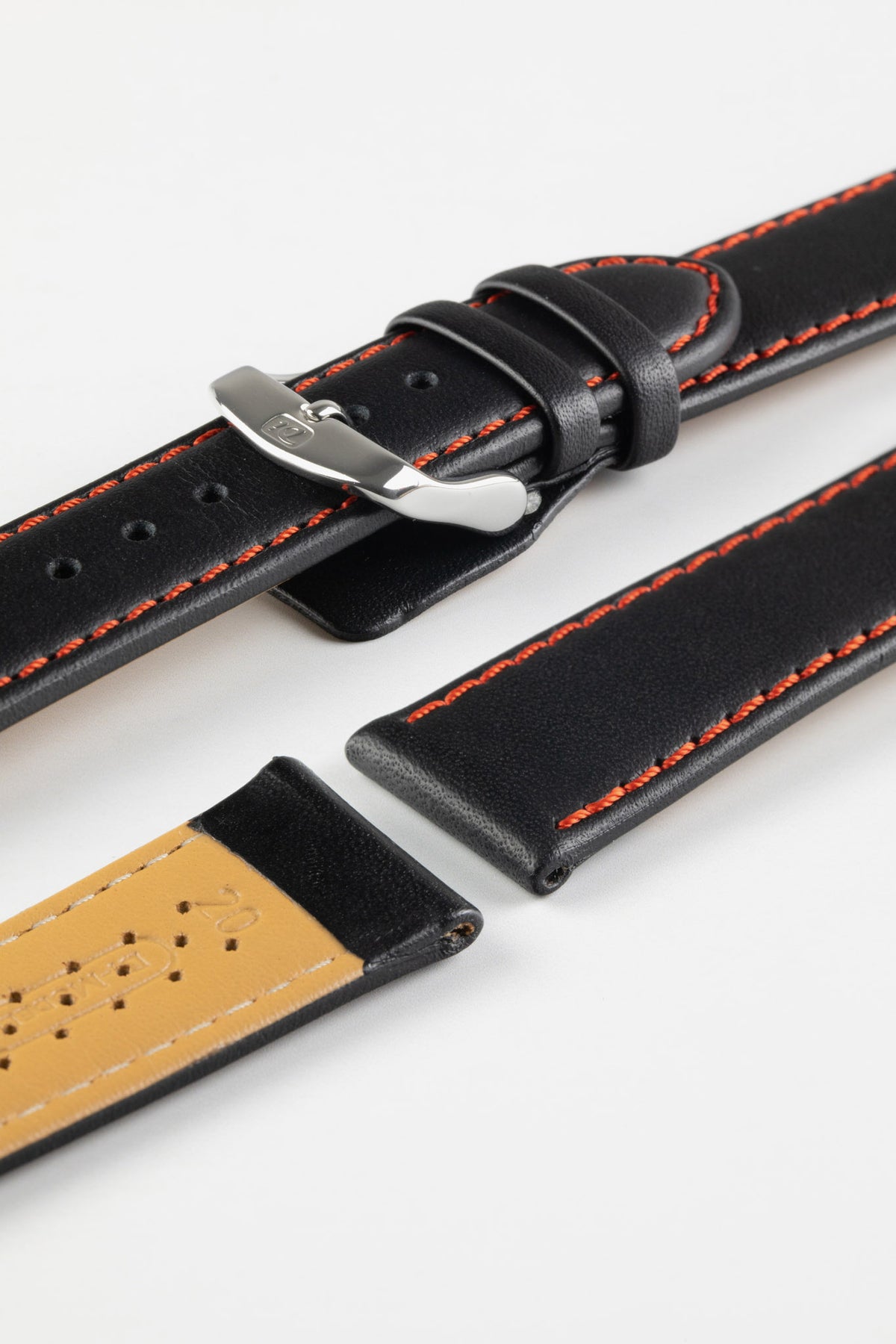 Black leather watch strap with red contrast stitching, beige perforated leather lining, and a polished stainless steel buckle, displayed on a white background.