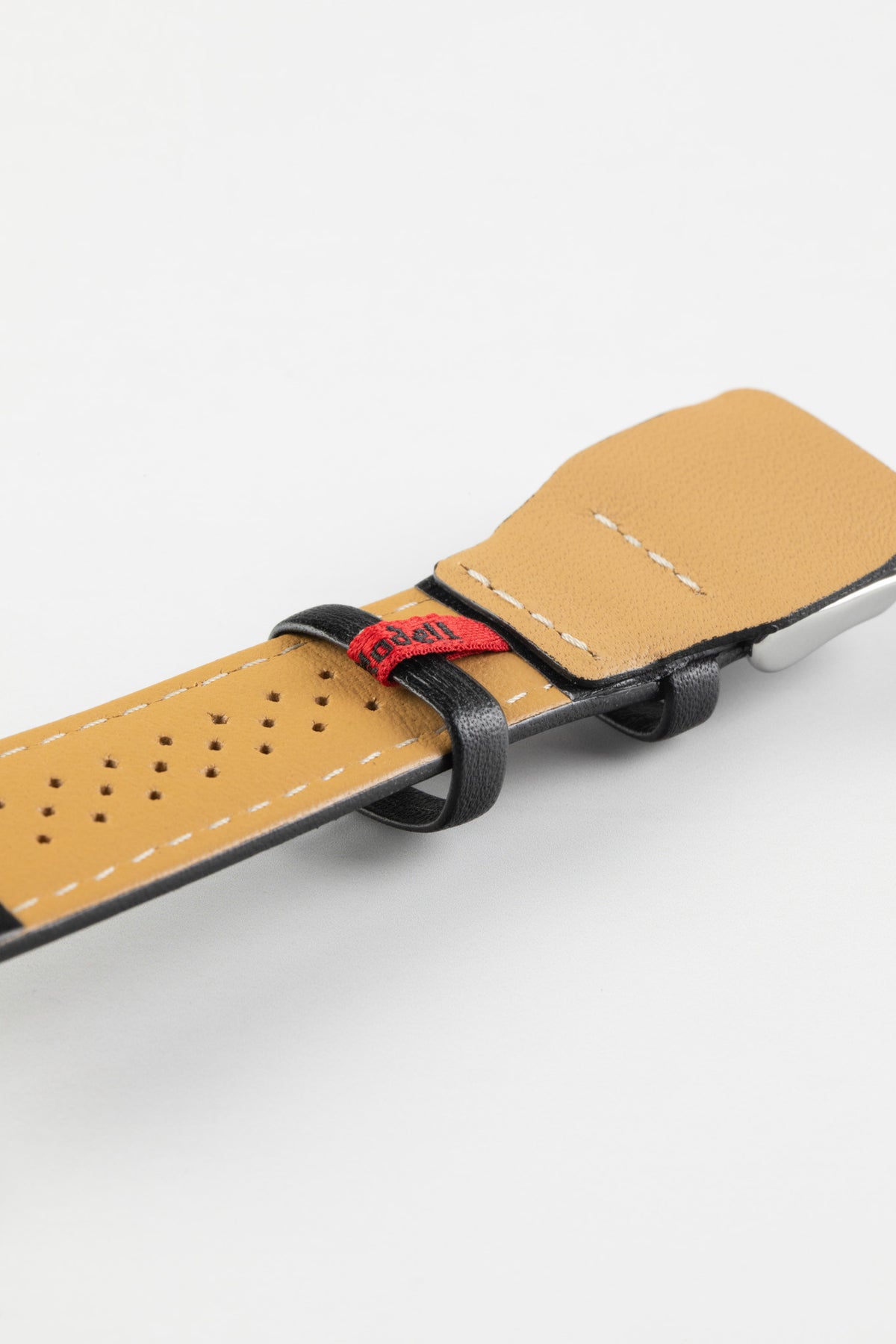 Black leather watch strap with a beige perforated leather lining, white contrast stitching, and a red branded