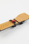 Black leather watch strap with a beige perforated leather lining, white contrast stitching, and a red branded