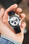 Seiko Speedtimer chronograph with a black alligator-grain leather strap, shown in hand with a white panda dial and black tachymeter bezel.