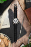 Seiko Speedtimer chronograph on a black alligator-grain leather strap, displayed with watchmaking tools and vintage accessories on a rustic wooden surface.