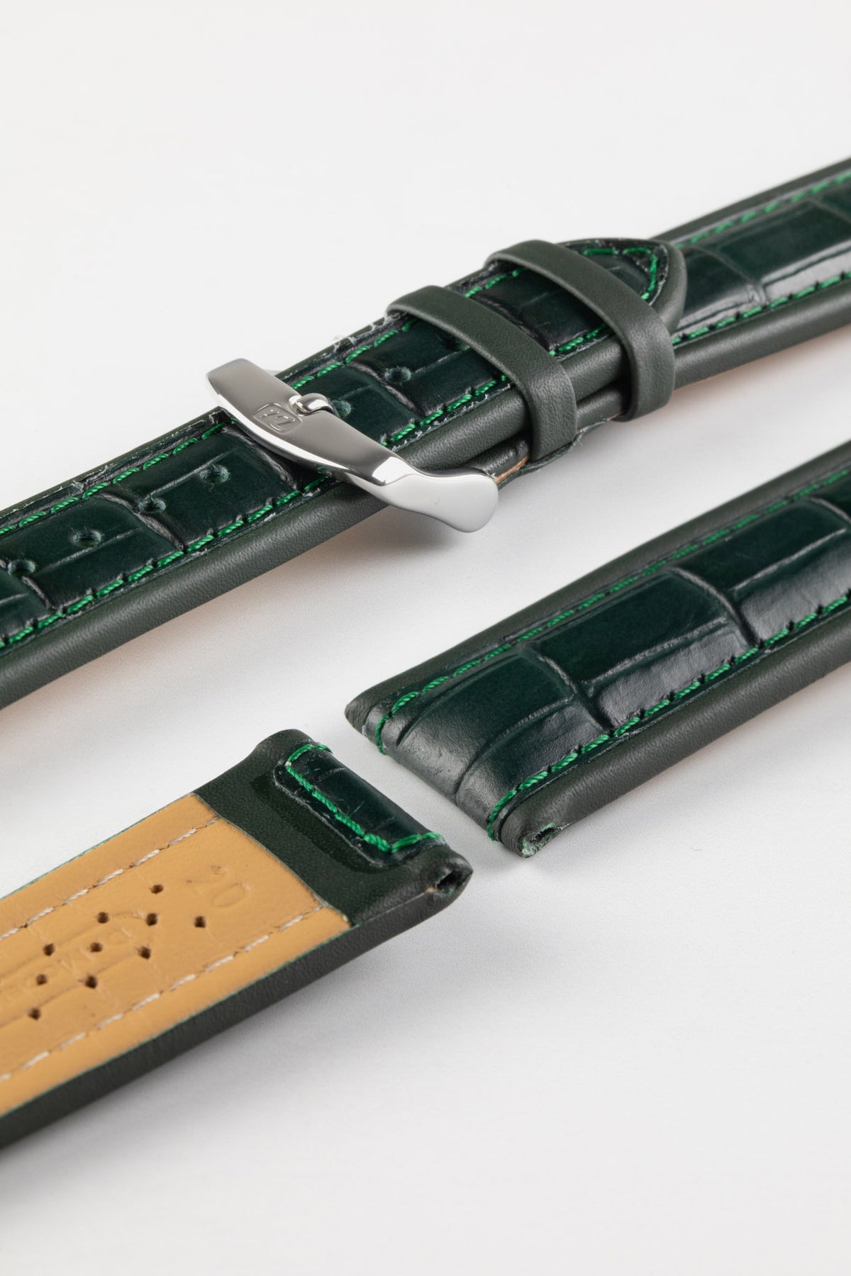 Dark green alligator-grain leather watch strap with green contrast stitching, a polished stainless steel buckle, and beige leather lining, displayed on a white background.