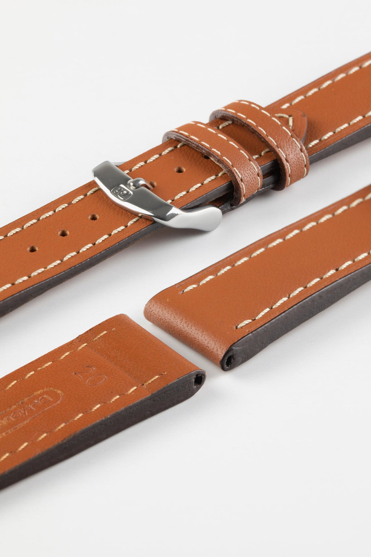 Close-up product photograph of a tan vintage-style leather watch strap displayed on a white background. The strap is shown in multiple sections, highlighting the smooth leather finish, contrasting cream stitching, polished stainless steel pin buckle, matching leather keepers, and dark brown edge finishing. The padded construction and elongated stitched channels showcase the strap's classic design, premium craftsmanship, and comfortable everyday wear.