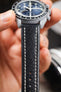 Black vintage-style leather watch strap fitted to an Omega x Swatch MoonSwatch chronograph, highlighting the cream contrast stitching and smooth leather finish.
