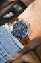 Omega Seamaster Diver 300M watch on a brown leather strap with cream contrast stitching, shown on wrist with a blue dial and matching blue bezel.