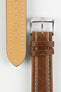 Close-up product photograph of a brown vintage-style leather rally watch strap displayed on a white background. The image shows both the top and underside of the strap, highlighting the smooth distressed leather finish, contrasting cream stitching, beige leather lining, matching brown leather keepers, and a polished stainless steel pin buckle engraved with the manufacturer's logo. The photograph showcases the strap's premium craftsmanship, padded construction, and classic motorsport-inspired design.