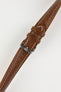 Product photograph of a brown vintage-style leather rally watch strap displayed on a white background. The strap features a smooth distressed leather finish, contrasting cream stitching, multiple sizing holes, matching brown leather keepers, and a polished stainless steel pin buckle engraved with the manufacturer's logo. The image highlights the strap's padded construction, tapered profile, and classic motorsport-inspired design.