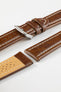 Close-up product photograph of a brown vintage-style leather rally watch strap displayed on a white background. The strap is shown in multiple sections, highlighting the smooth distressed leather finish, contrasting cream stitching, polished stainless steel pin buckle, and beige perforated leather lining. The padded construction and elongated perforated rally channels showcase the strap's motorsport-inspired design, premium craftsmanship, and comfortable wear.