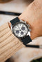Seiko Speedtimer chronograph watch worn on the wrist, featuring a white panda dial with three dark blue chronograph sub-dials, black tachymeter bezel, stainless steel case, and a dark navy leather watch strap with tonal stitching, paired with a cream knitted sweater cuff to highlight the strap's smooth matte finish, minimalist design, and versatile everyday style.