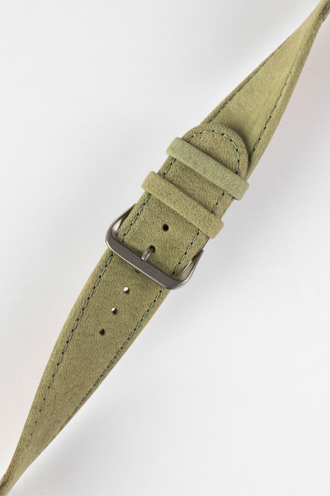 Close-up of a sage green nubuck leather watch strap with a soft matte finish, tonal green stitching, dual keeper loops, multiple adjustment holes, and a polished stainless steel buckle, displayed diagonally on a light grey background to highlight the tapered profile, vintage-inspired suede texture, and premium handcrafted construction.