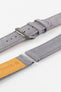Close-up detail view of a light grey nubuck leather watch strap displayed with one strap section detached, featuring a soft suede-like texture, tonal grey stitching, dual keeper loops, multiple adjustment holes, a brushed stainless steel buckle, and a natural tan leather lining embossed with the Di-Modell logo and size marking, shown on a light grey background to highlight the premium handcrafted construction and quick-release spring bar compatibility.