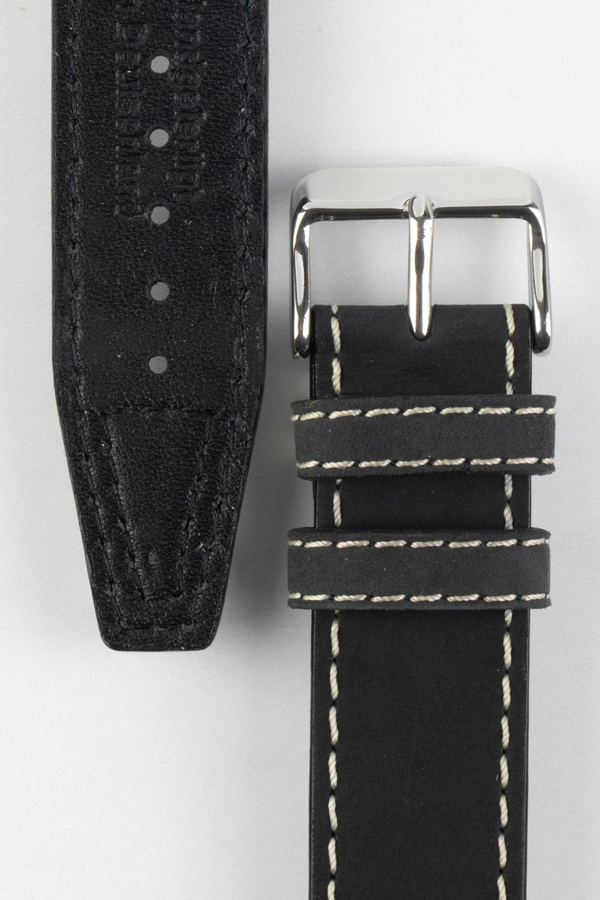 Front and back detail view of a black leather watch strap featuring a smooth matte finish, contrasting cream stitching, dual keeper loops, a polished stainless steel buckle, and a black leather lining with embossed manufacturing details, displayed on a light grey background to highlight the premium handcrafted construction, contrasting stitching, and vintage-inspired design.
