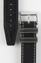 Front and back detail view of a black leather watch strap featuring a smooth matte finish, contrasting cream stitching, dual keeper loops, a polished stainless steel buckle, and a black leather lining with embossed manufacturing details, displayed on a light grey background to highlight the premium handcrafted construction, contrasting stitching, and vintage-inspired design.