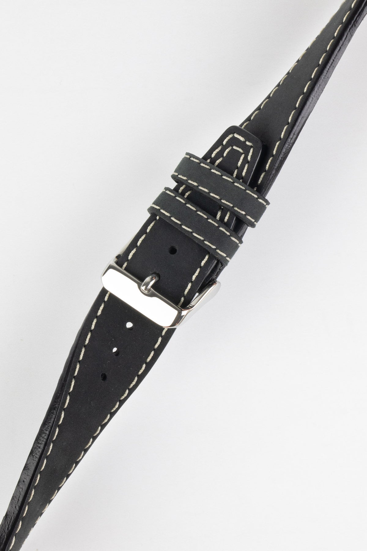 Close-up of a black leather watch strap with a smooth matte finish, contrasting cream stitching, tapered pointed tip, dual keeper loops, multiple adjustment holes, and a polished stainless steel buckle, displayed diagonally on a light grey background to highlight the vintage-inspired design, premium handcrafted construction, and refined leather detailing.
