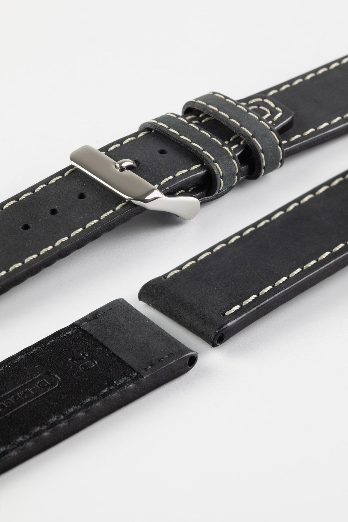 Close-up detail view of a black leather watch strap displayed with one strap section detached, featuring a smooth matte finish, contrasting cream stitching, dual keeper loops, multiple adjustment holes, a polished stainless steel buckle, and a black leather lining embossed with the Di-Modell logo and size marking, shown on a light grey background to highlight the premium handcrafted construction, tapered profile, and quick-release spring bar compatibility.