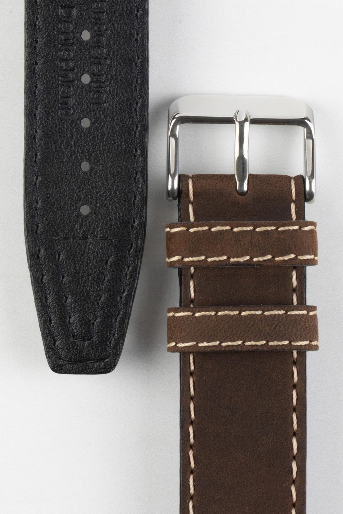 Front and back detail view of a dark brown leather watch strap featuring a smooth vintage-style finish, cream contrast stitching, dual keeper loops, a polished stainless steel buckle, and a black leather lining embossed with manufacturing details, displayed on a light grey background to highlight the premium handcrafted construction, contrasting underside, and classic heritage-inspired design.