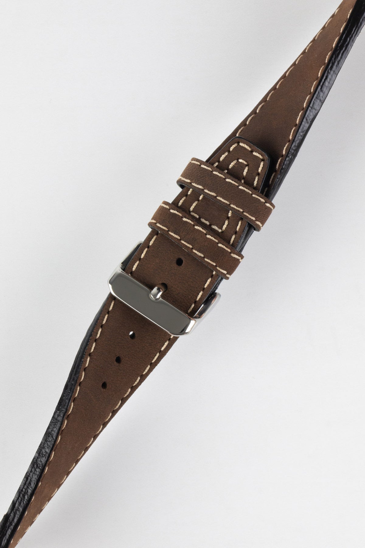 Close-up of a dark brown leather watch strap with a smooth vintage-style finish, cream contrast stitching, tapered pointed tip, dual keeper loops, multiple adjustment holes, and a polished stainless steel buckle, displayed diagonally on a light grey background to highlight the rich leather patina, premium handcrafted construction, and classic heritage-inspired design.